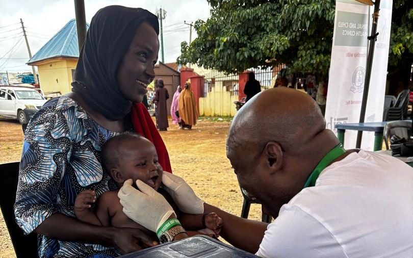 An NIDSG doctor examining a smiling baby at a maternal and child health clinic